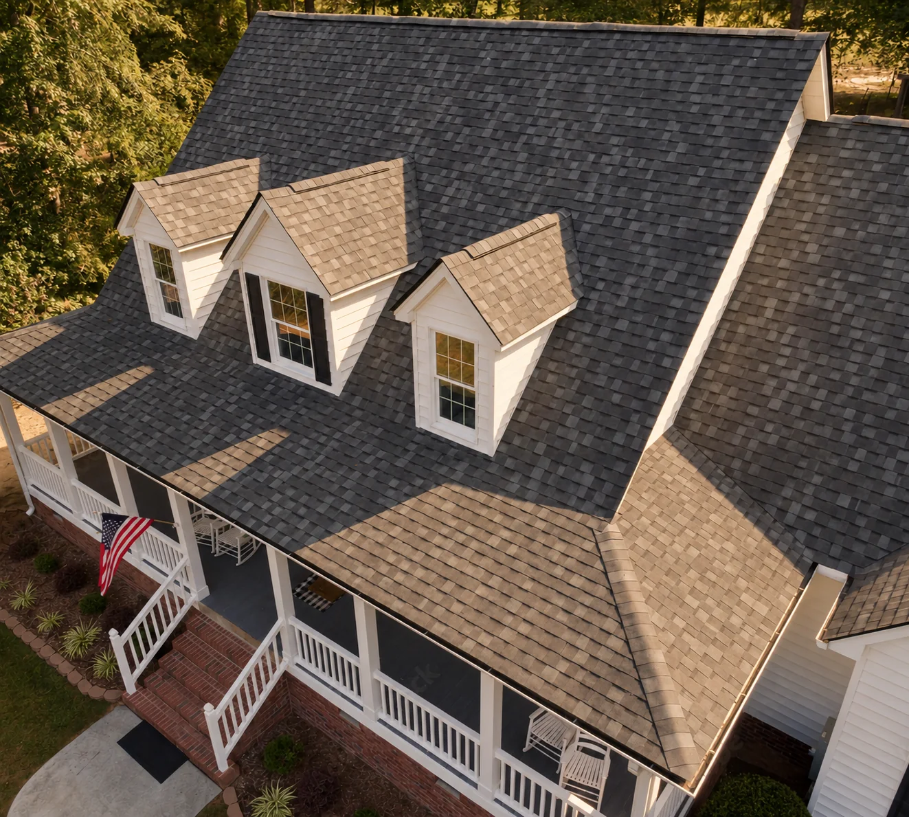 Finished shingle roof with three dormer windows above a welcoming front porch